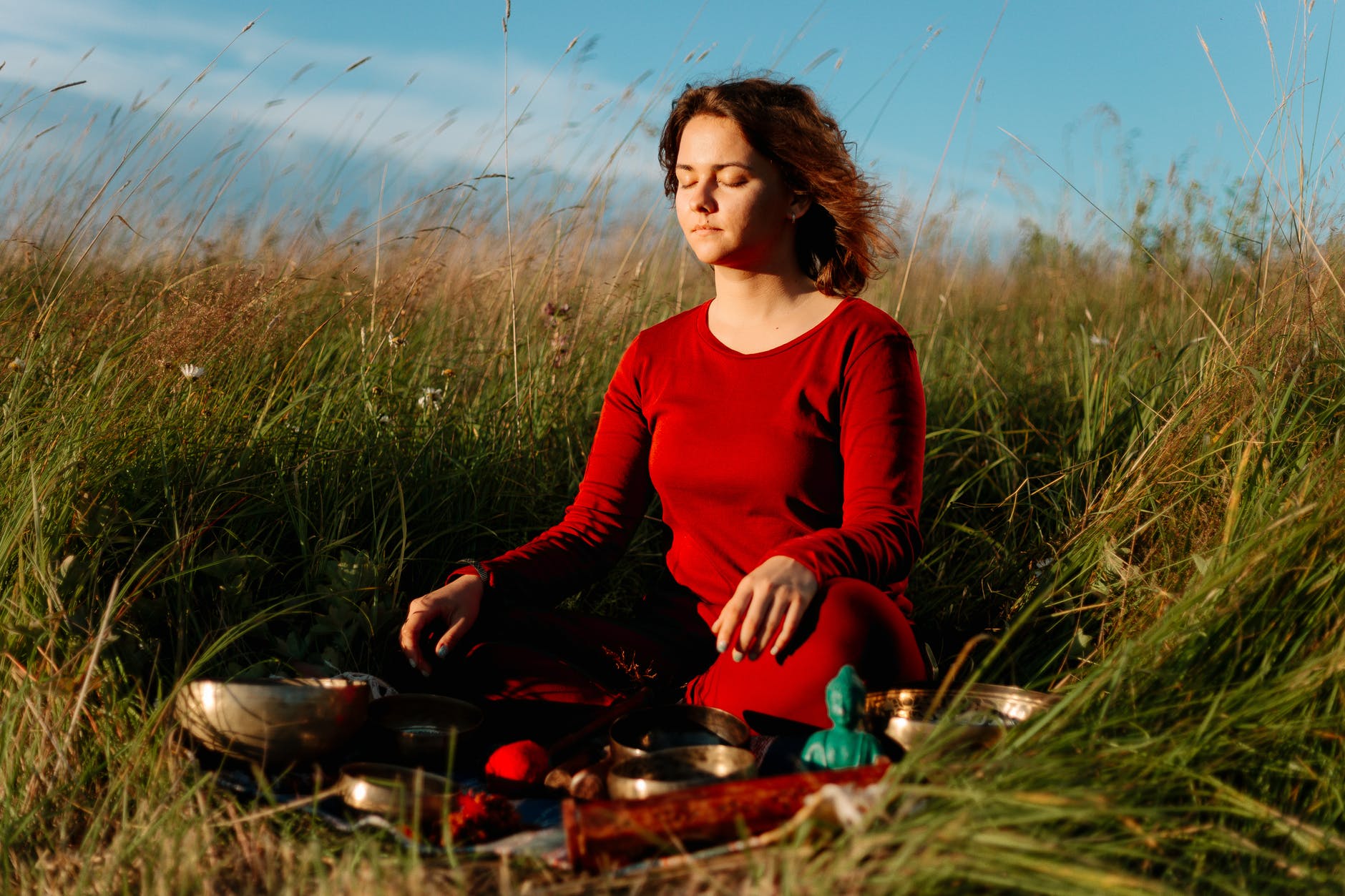 woman in red long sleeve shirt sitting on grass field